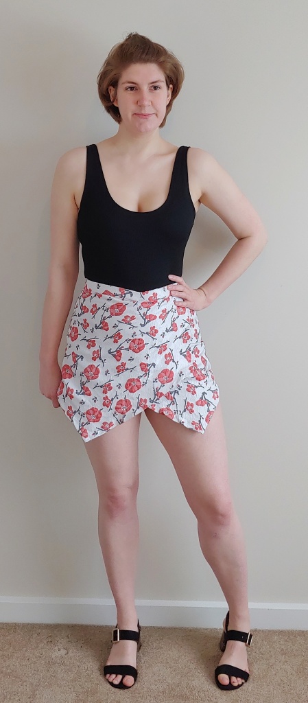 Helen wearing a black vest top and jackquard shorts, which are cream with a red floral pattern.