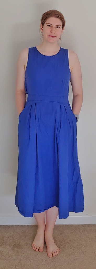 Full length photo of Helen wearing a royal blue, mid-shin length sleeveless dress.